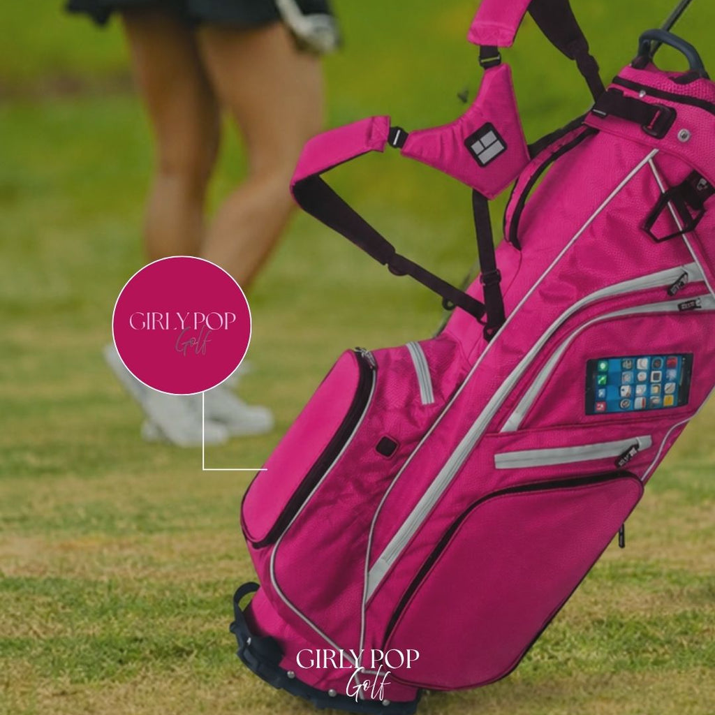 Pink golf bag with 'GIRLY POP' branding on a grassy field.