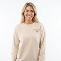 Woman wearing a beige sweatshirt with a logo on a white background