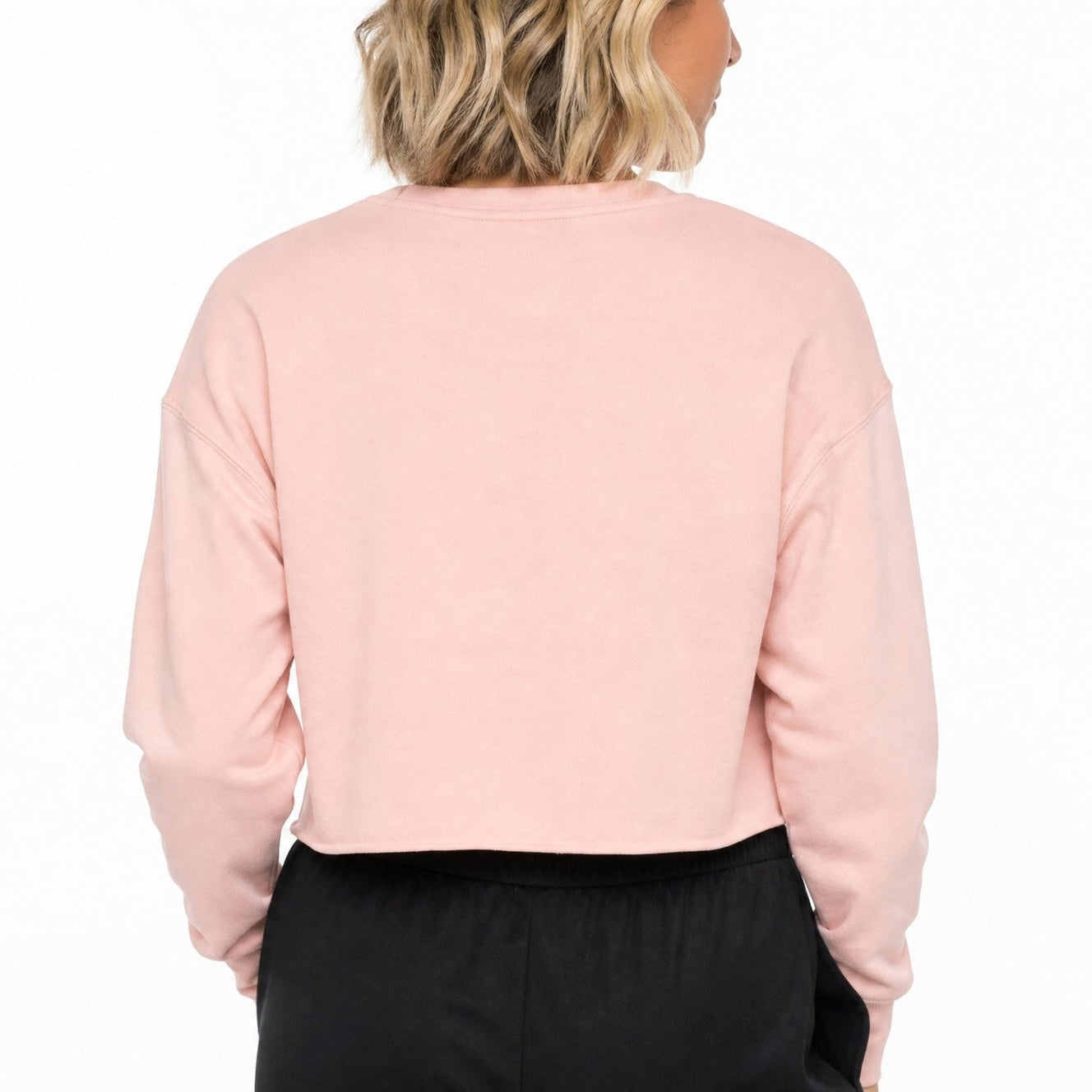 Person wearing a light pink sweater and black pants on a white background