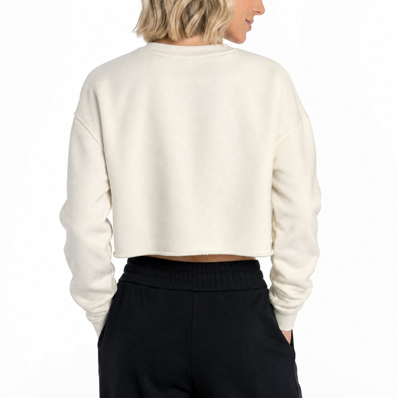 Person wearing a cream sweater and black pants on a white background